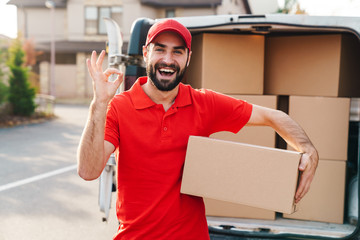 Image of a delivery man standing with parcel box and showing ok sign