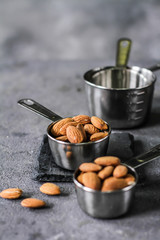 Photo of almond in the bowl on dark background. Almond with spoon or scoop. Raw whole almond. Almond concept with copyspace. Images.