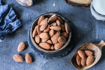 Photo of almond in wooden bowl on dark background. Top view of almond. Almond with wooden spoon or scoop. Almond concept. Images.