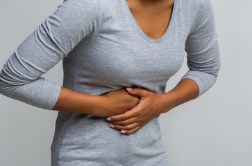 Black woman suffering from gastritis, touching her tummy