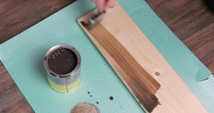 Painting lumber with wood stain coloring with paint brush