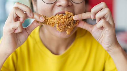 Young woman holding and eating fries chicken