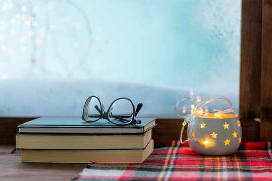 cozy winter window sill with books and warm blanket
