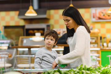 Obraz na płótnie Canvas woman and child boy during family shopping with trolley at supermarket