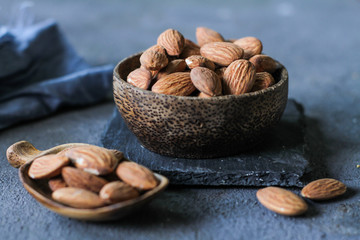 Photo of almond in a wooden bowl. Front View of almond. Almond with wooden spoon or scoop. Raw almond on the table. On rustic board. Images