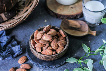 Photo of almond in wooden bowl on gray background. Almond with wooden spoon or scoop. Raw whole almond. Almond milk. Images