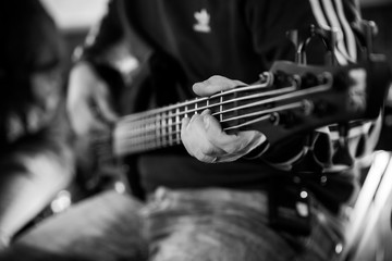 Musiker spielt auf fünfsaitigem E-Bass, schwarz-weiß