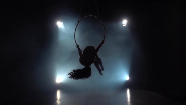 Aerial acrobat in the ring. A young girl performs the acrobatic elements in the air ring. Slow motion. 001