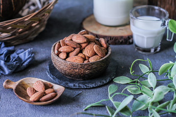 Photo of almond in wooden bowl on gray background. Almond with wooden spoon or scoop. Raw whole almond. Almond milk. Images