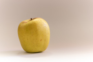 Close up of a golden apple on a grey background