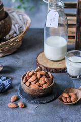 Photo of almond in wooden bowl on gray background. Almond with wooden spoon or scoop. Raw whole almond. Almond milk. Images