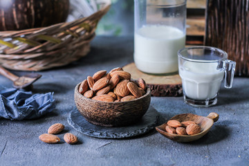 Photo of almond in wooden bowl on gray background. Almond with wooden spoon or scoop. Raw whole almond. Almond milk. Images