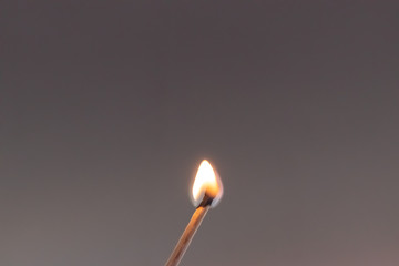 Burning match in a grey plain background
