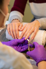 Beautician using the cuticle cutter on client's nails.