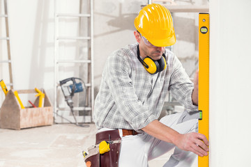 Builder using a spirit level to measure a wall