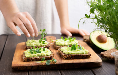 Girl preparing sandwiches with avocado spread and microgreen