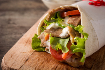 Doner kebab or shawarma sandwich on wooden table. Close up	