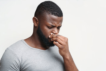 Afro man touching his nose, having runny nose