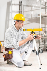 Builder using a tripod spirit level kneeling down