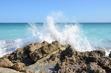 Fototapeta na wymiar blue ocean water splashing on rocks on the beach
