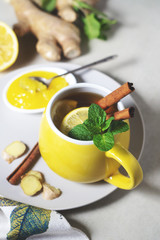 Tea with lemon, ginger, honey and cinnamon in a yellow cup