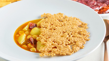 Fresh hot soup sauce of soybeans, potatoes and cheese chips above in the white bowl closeup. Healthy mediterranean food.