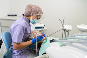 A dentist uses ultrasound and a saliva ejector to clean a patient’s dental calculus.