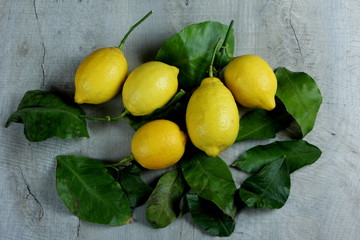 Fresh juicy fruit lemon on a wooden background with leaves. Lemon with leaves on wooden background 