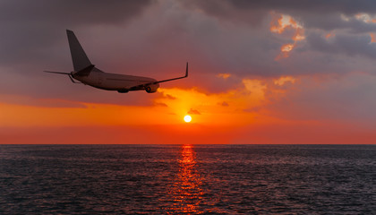 Passenger plane flying over the sea orange sunset