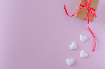 Gift box and white heart on a pink background. Valentine's day and romantic concept. Flat lay. Copy space.