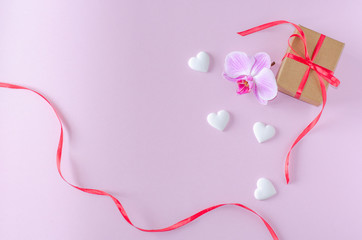 Gift box, orchid flower and white hearts on a pink background. Valentine's day and romantic concept. Flat lay. Copy space.