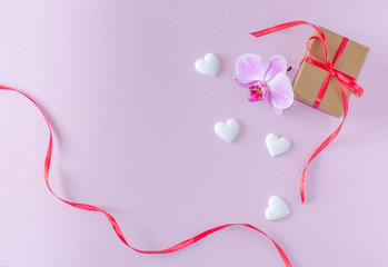 Gift box, orchid flower and white hearts on a pink background. Valentine's day and romantic concept. Flat lay. Copy space.