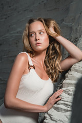 Fototapeta premium blonde girl sitting at sandy beach. Outdoor portrait of pretty curly woman. beauty retouch