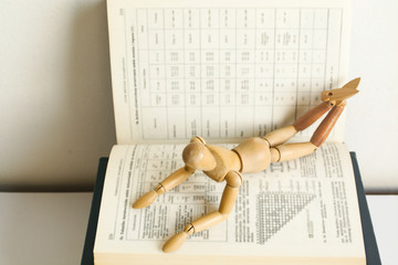 Obraz premium Wooden mannequin manikin lie down on open book and learning with pleasure. He is thinking of mastering the material. A metaphor for studying. Good student. Interest in learning. Education. PhD studies