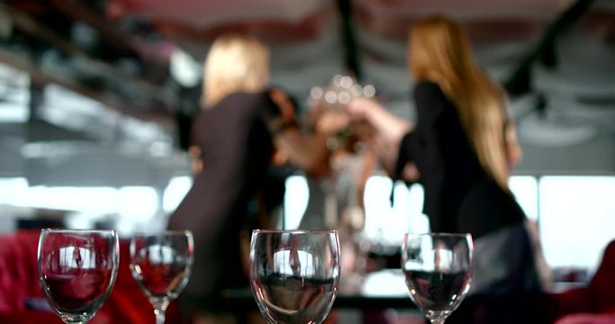 a group of girls in glittering dresses sit, stand, and dance around a cocktail table