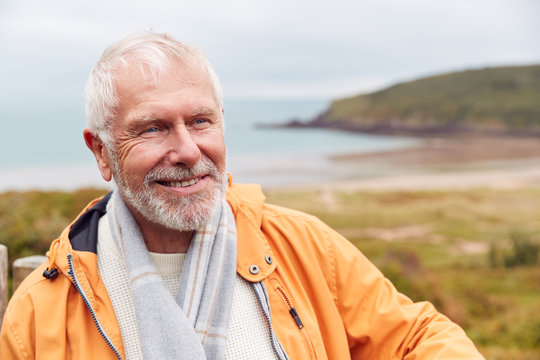Active Senior Man Walking Along Coastal Path In Fall Or Winter By Gate With Beach And Cliffs Behind - Powered by Adobe