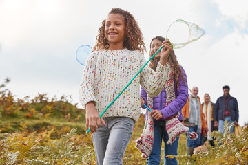 Multi-Generation Family Walking Through Countryside Carrying Fishing Nets On Winter Beach Vacation