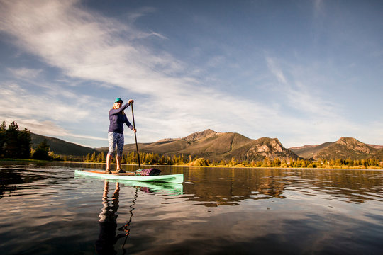 One woman paddle boarding on Lake Dillon in Summit County, Colorado in the early morning.