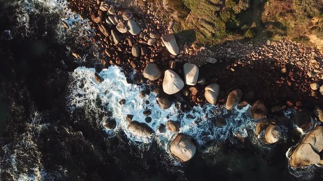 4K sunny summer sunrise aerial drone camera down video of Atlantic Ocean boulders coastal beach on the outskirts of Simon's Town en route to Cape Of Good Hope, Western Cape, South Africa