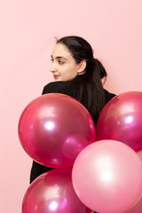 Young pretty woman in casual clothing holding festive air balloons. Portrait of happy 20s middle-eastern female celebrating valentines day, birthday, party