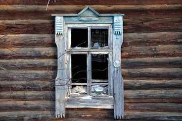 Window with platbands in an old wooden house, glass is smashed.
