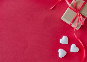 Fototapeta premium Gift box and white hearts on a red background. Valentine's day and romantic concept. Flat lay. Copy space.