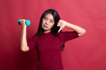 Fototapeta premium Unhappy Asian woman thumbs down with dumbbells.