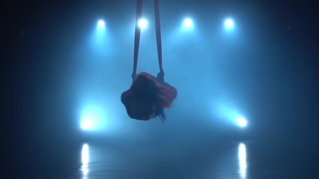 Graceful gymnast performing xercise with red silk on blue light background. Slow motion. 170