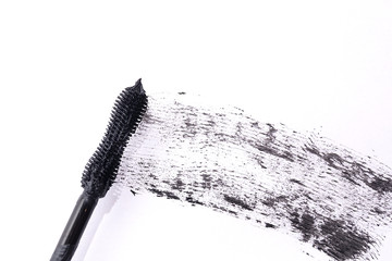 Applicator and black mascara smear for eyelashes on white background. Top view.
