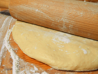 Rolling pin and yeast dough on flour-covered table. Homemade baking.    