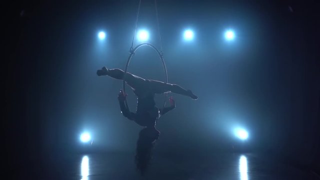 Aerial acrobat in the ring. A young girl performs the acrobatic elements in the air ring in the circus. Slow motion. 176