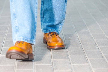 Close-up of Male Legs In Leather Brown Oxford Semi Brogues Shoes. Photographed in Motion While...