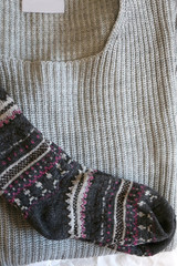 Grey knit sweater and patterned wool socks. Top view.