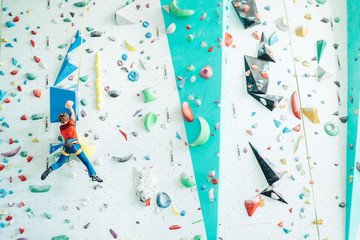 Teenager boy at indoor climbing wall hall. Boy is climbing using an auto belay system and climbing...